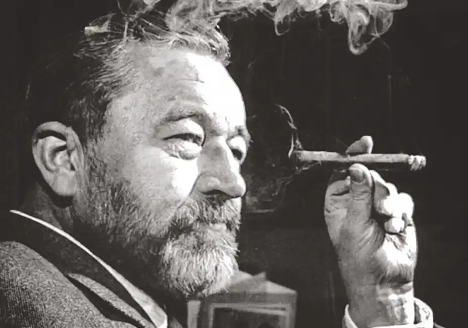 A black and white photograph of Jan Werich smoking a cigar, radiating his iconic charm and charisma as a legendary Czech actor and humorist.