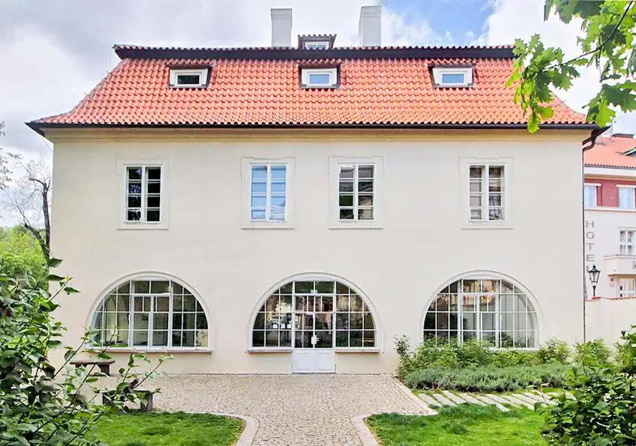 An exterior view of the Werich Villa in Prague, a historic building surrounded by lush greenery on the island of Kampa, underlining its cultural significance as a centre of Czech art and history.